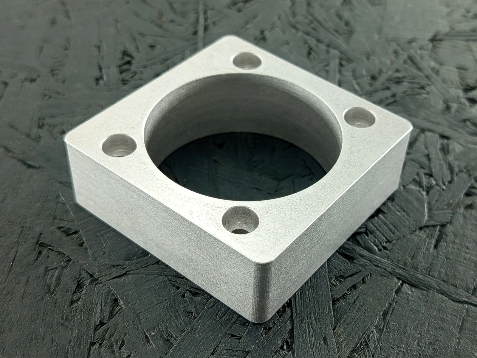 CNC-gefräster Halter aus Alu 5083, 20mm dick, mit zentraler Tasche und vier Gewinden.