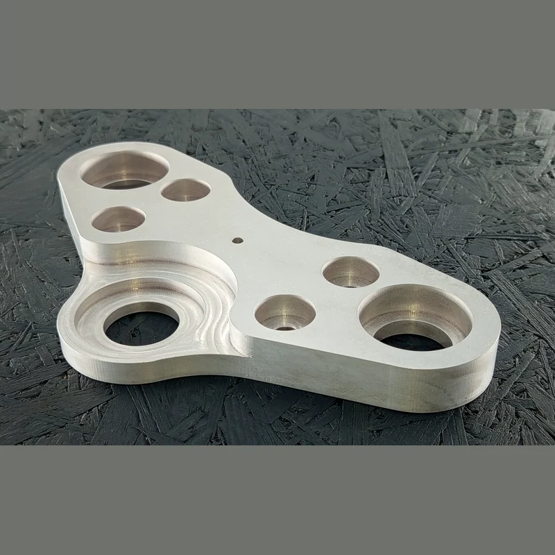 CNC-gefräster Halter aus Alu 7075, 20mm dick, mit Taschen und Bohrungen auf dunklem Hintergrund.