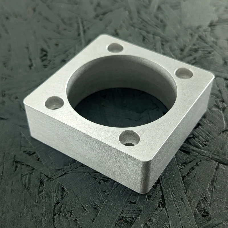 CNC-gefräster Halter aus Alu 5083, 20mm dick, mit zentraler Tasche und vier Gewinden.