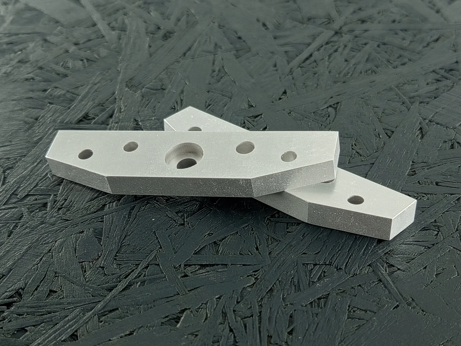 Zwei CNC-gefräste Flansche aus Aluminium 5083, 8mm dick, mit Bohrungen und Tasche, auf dunklem Hintergrund.