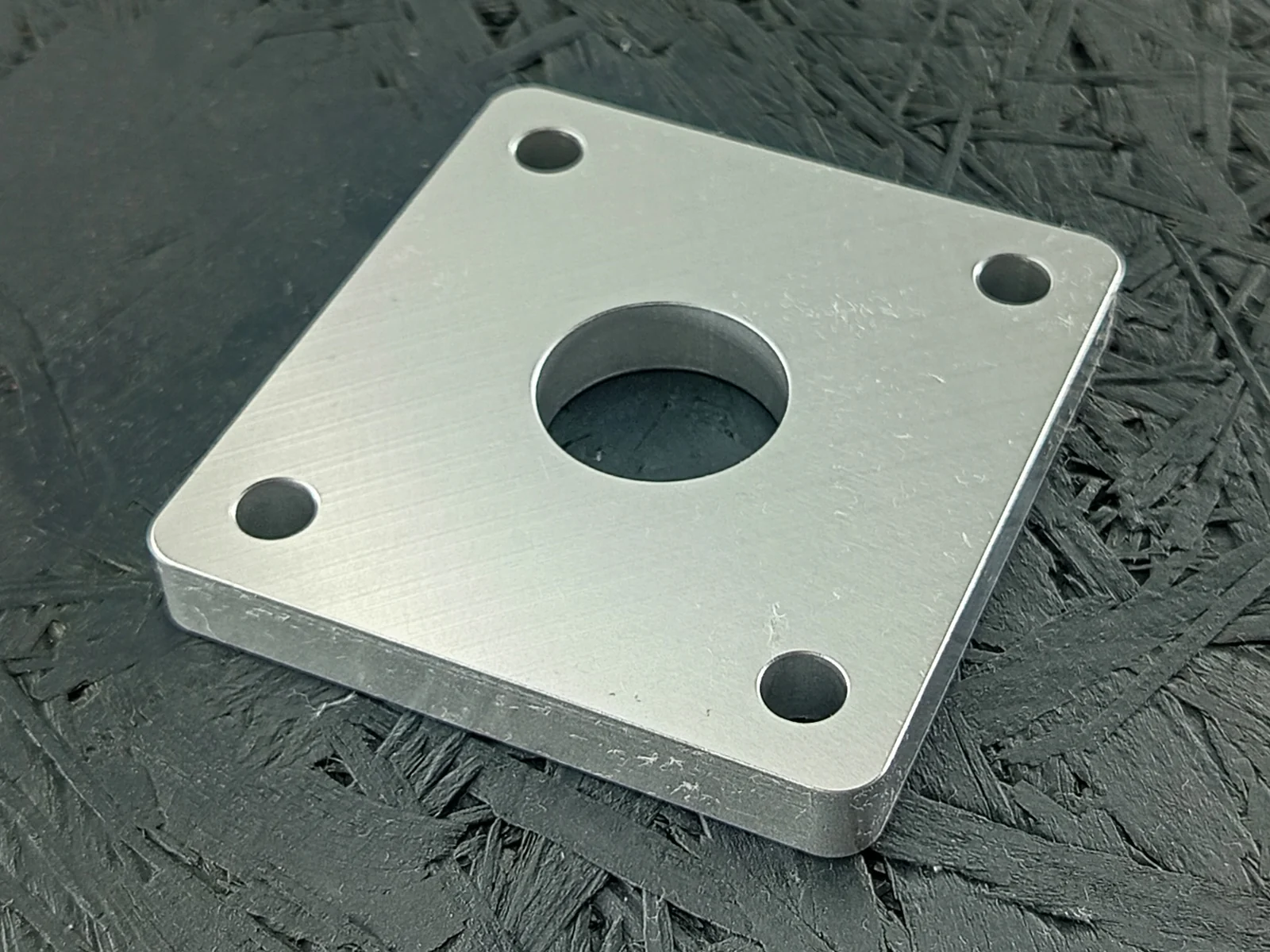 CNC-gefräste Adapterplatte aus Aluminium 5083, 10mm dick, mit zentraler Bohrung und vier Eckbohrungen.