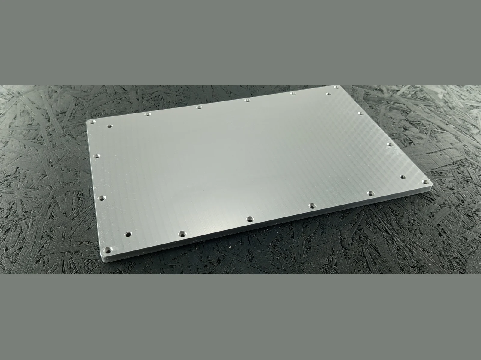 Rechteckige Aluminium-Adapterplatte aus Alu 5083 mit Bohrungen und Fasen, 8 mm dick, auf dunklem Untergrund