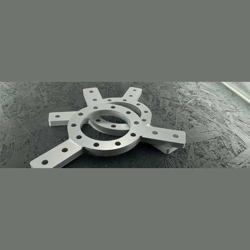 Zwei CNC-fräsgefräste Adapterplatten aus Alu 5083 auf dunklem Untergrund, mit zentraler Bohrung und vier Anschlussarmen